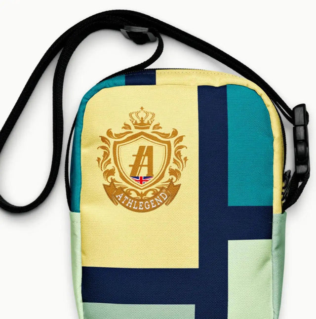A colorful patchwork crossbody bag with a gold crest logo and black adjustable strap.