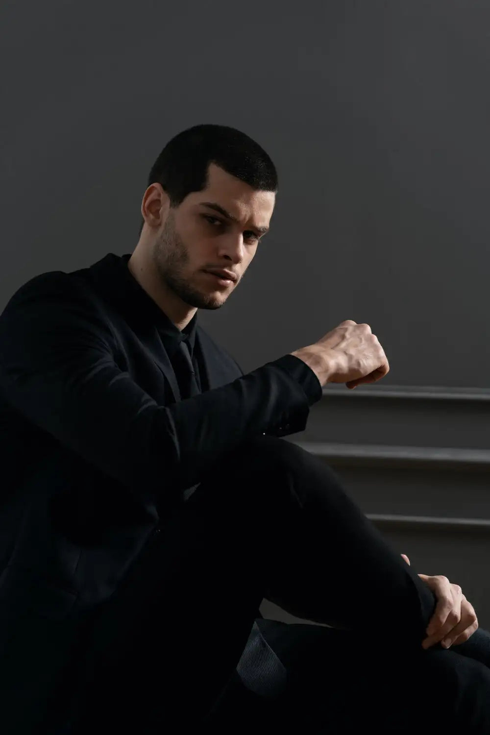 A man wearing a sleek black suit with subtle texture and tailored fit.